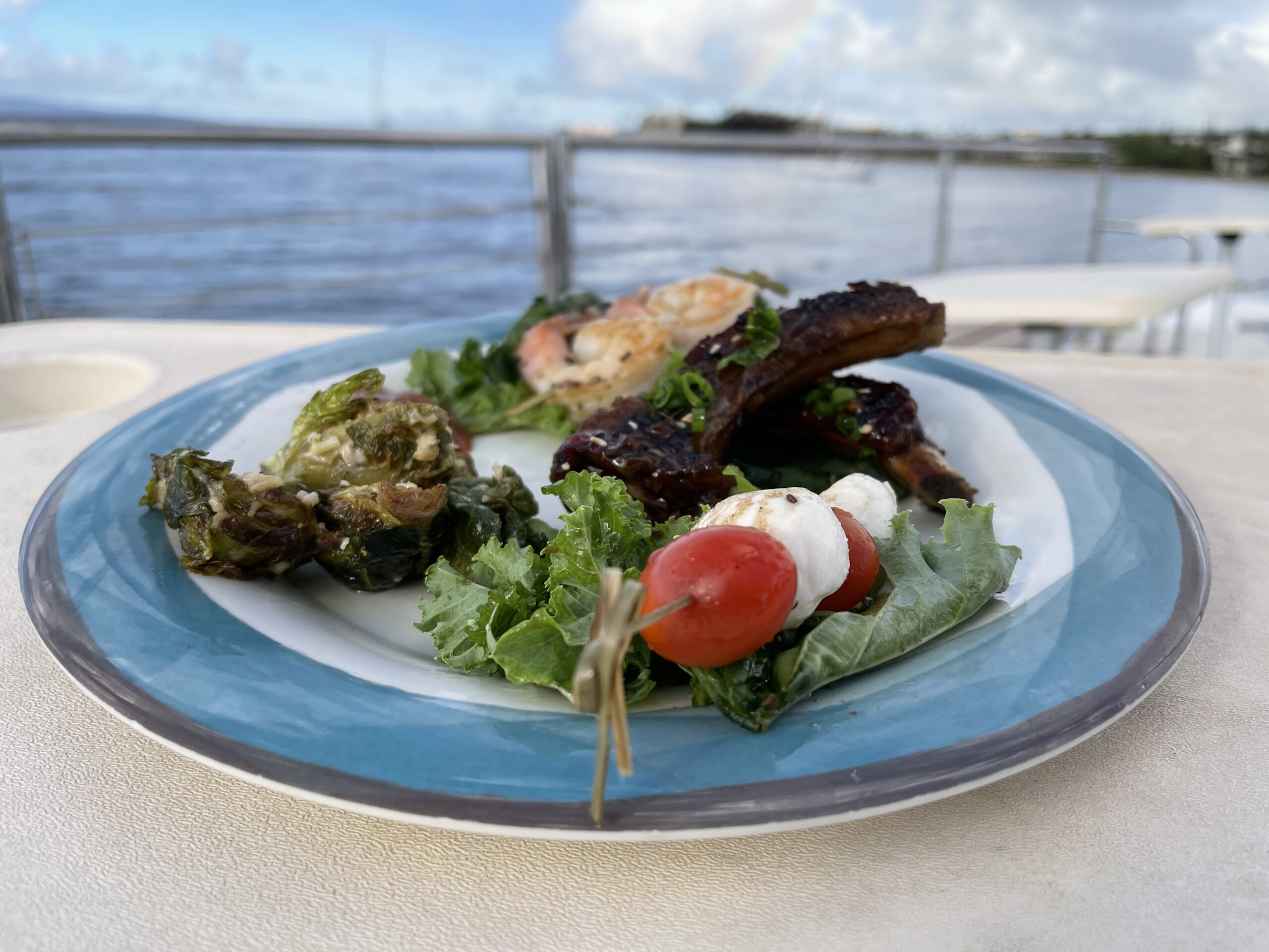 Plate of assorted food with a waterfront view.