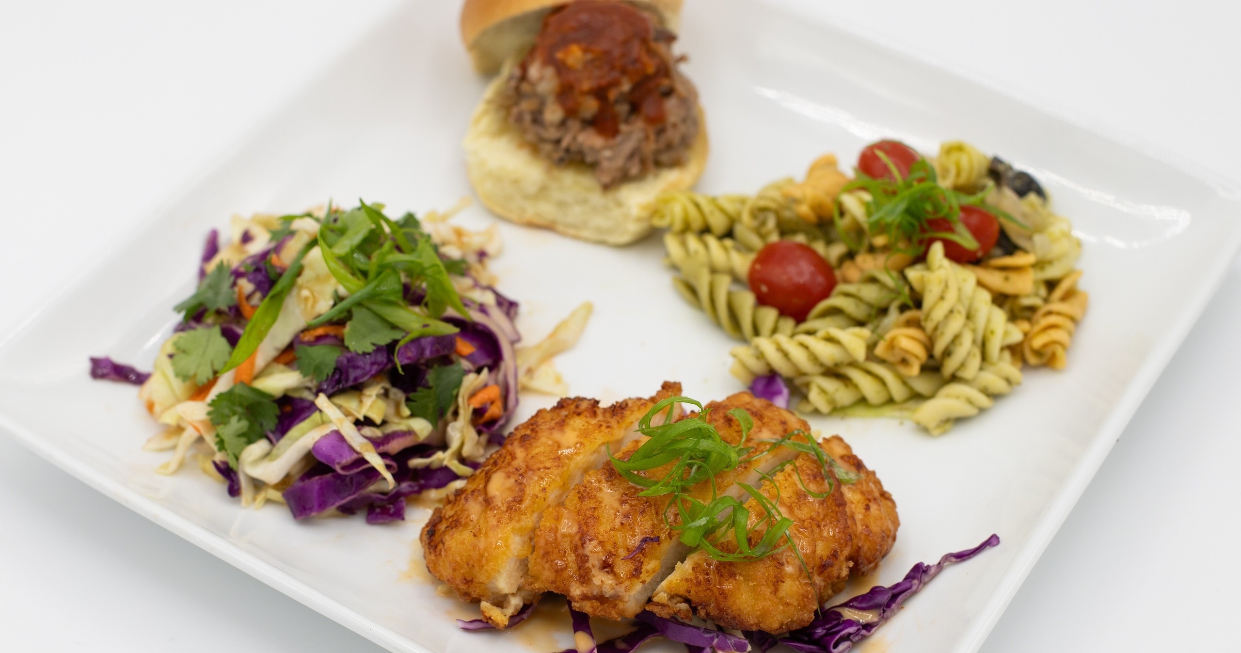 Plate with coleslaw, chicken, pasta salad, and a small sandwich.