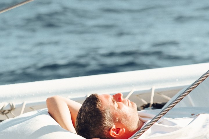 Person relaxing on a boat, lying on a cushion by the sea.